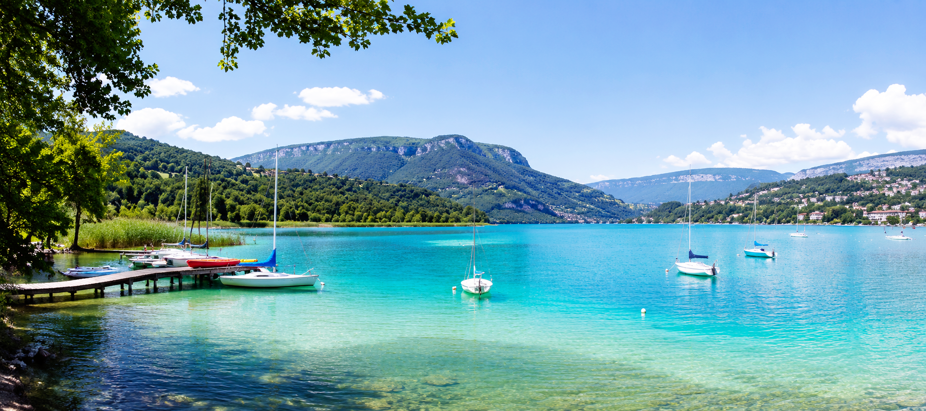 Vue panoramique du lac de Paladru en Isère, avec ses eaux turquoise, ses voiliers et ses plages, destination idéale pour une escapade romantique en amoureux.
